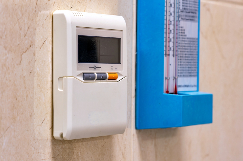 Thermostat on wall next to thermometer